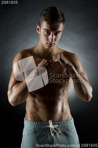 Image of young man on fighting stand over black background