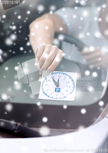 Image of close up of man putting parking clock