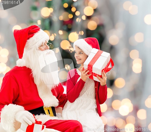 Image of smiling little girl with santa claus and gifts
