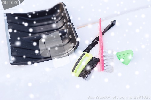 Image of black snowshowel with wooden handle in snow pile