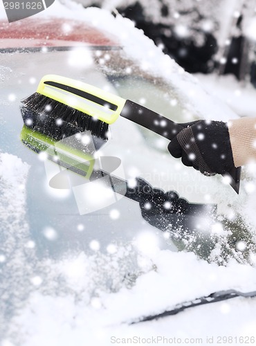 Image of closeup of man cleaning snow from car