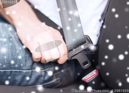 Image of close up of man fastening seat belt in car