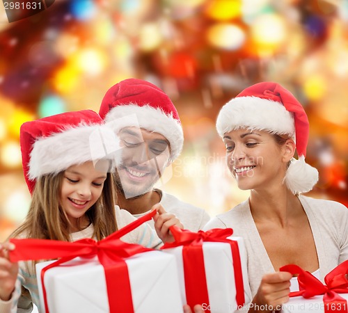 Image of happy family in santa helper hats with gift boxes