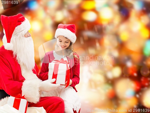 Image of smiling little girl with santa claus and gifts