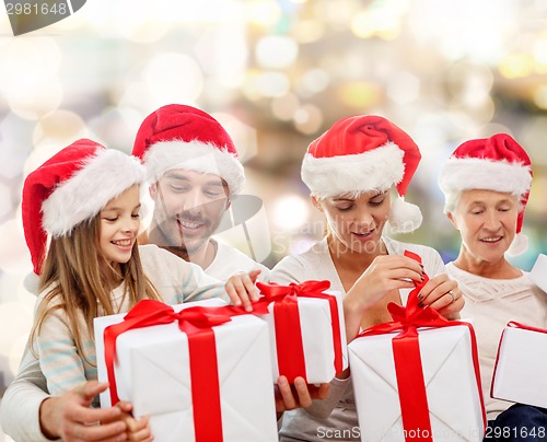 Image of happy family in santa helper hats with gift boxes