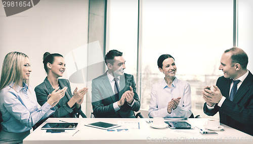 Image of business team with laptop clapping hands