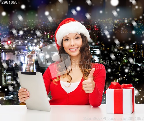 Image of smiling woman in santa hat with gift and tablet pc