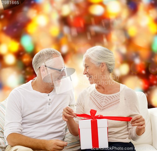 Image of happy senior couple with gift box at home