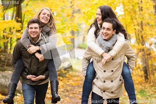 Image of smiling friends having fun in autumn park