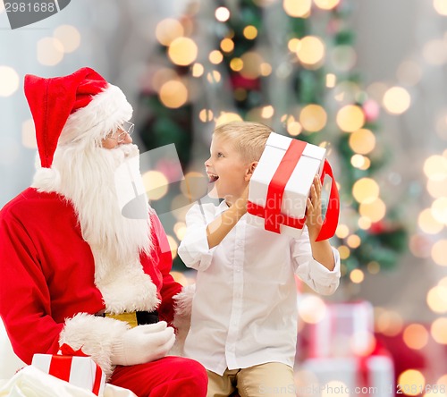 Image of smiling little boy with santa claus and gifts