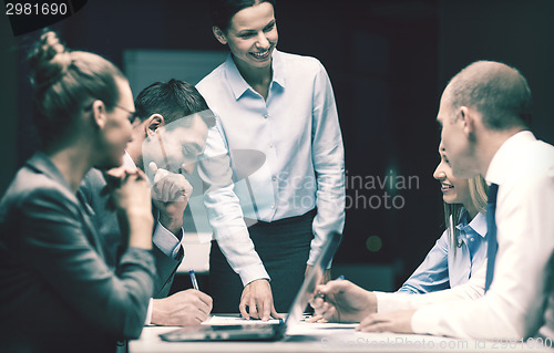 Image of smiling female boss talking to business team