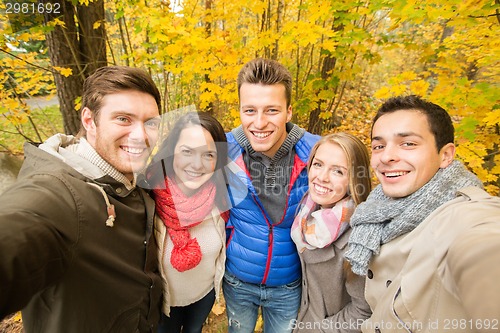 Image of group of smiling men and women in autumn park