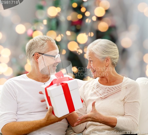 Image of happy senior couple with gift box at home