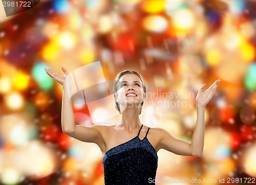 Image of smiling woman raising hands and looking up