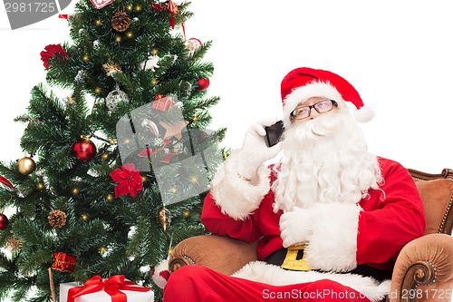 Image of santa claus with smartphone and christmas tree