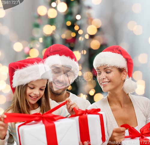 Image of happy family in santa helper hats with gift boxes