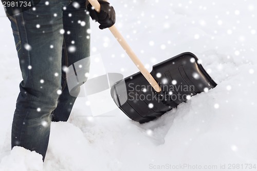 Image of closeup of man digging snow with shovel