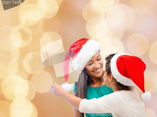 Image of happy mother and girl in santa hats