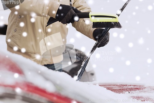 Image of closeup of man cleaning snow from car