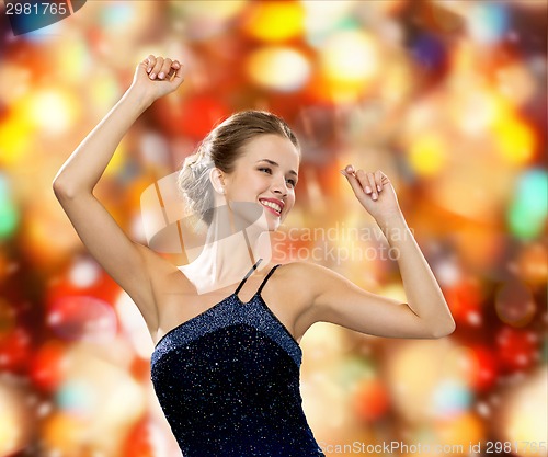 Image of smiling woman dancing with raised hands