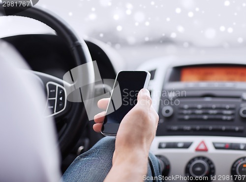 Image of close up of man using smartphone while driving car