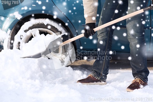 Image of closeup of man digging snow with shovel near car