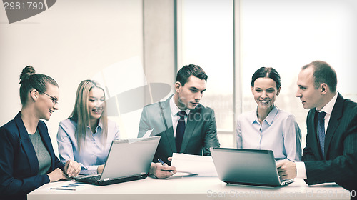 Image of business team with laptop having discussion