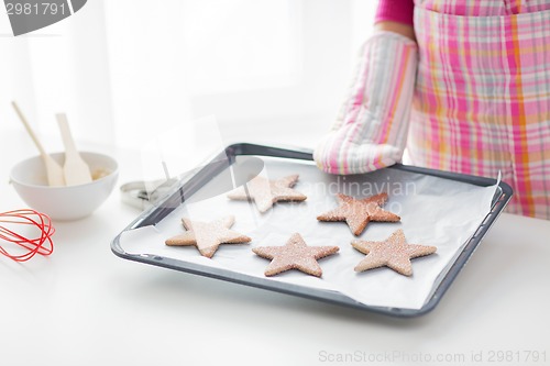 Image of close up of woman with cookies on oven tray