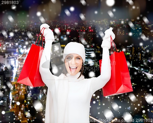 Image of smiling young woman with red shopping bags