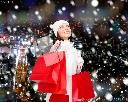 Image of smiling young woman with red shopping bags