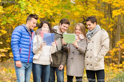 Image of group of smiling friends with tablets in park