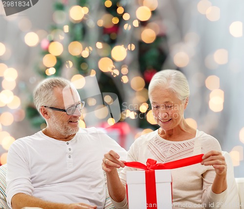 Image of happy senior couple with gift box at home