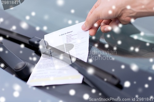 Image of close up of male hand with parking ticket on car