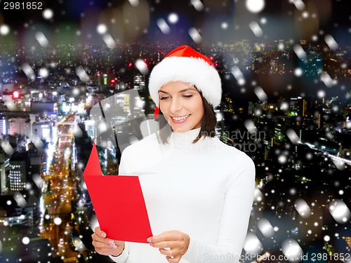 Image of smiling woman in santa hat with greeting card