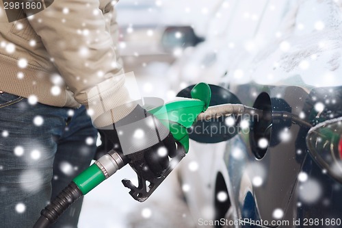 Image of close up of man with fuel hose nozzle tanking car