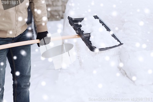 Image of closeup of man digging snow with shovel near car