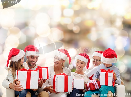 Image of happy family in santa helper hats with gift boxes