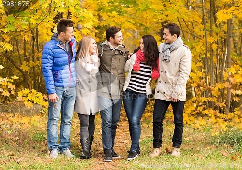 Image of group of smiling men and women in autumn park