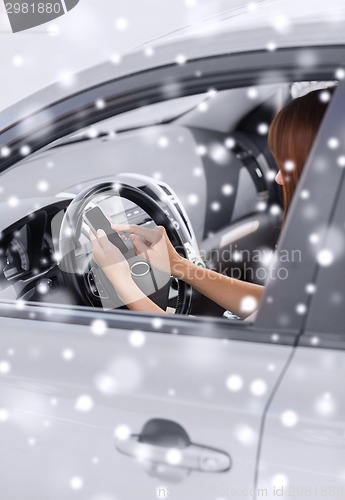 Image of close up of woman with smartphone driving car