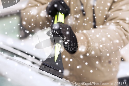 Image of closeup of man cleaning snow from car