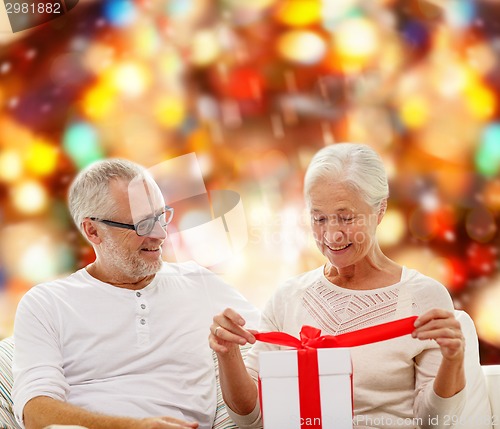 Image of happy senior couple with gift box at home