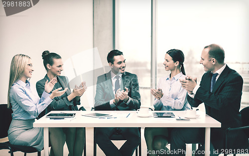 Image of business team with laptop clapping hands