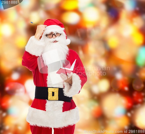 Image of man in costume of santa claus with notepad