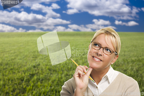 Image of Contemplative Woman in Grass Field Looking Up and Over