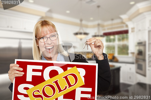 Image of Young Woman Holding Sold Sign and Keys Inside New Kitchen