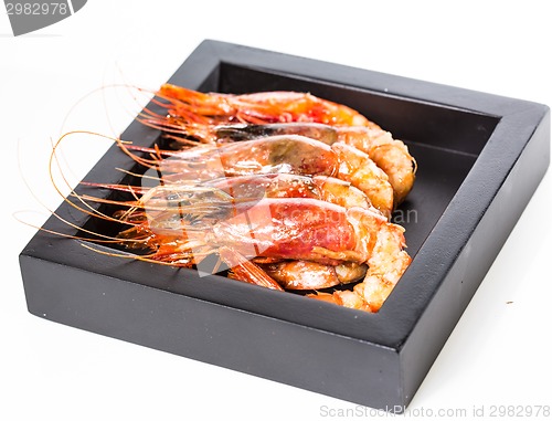 Image of grilled shrimp in black plate on white background.