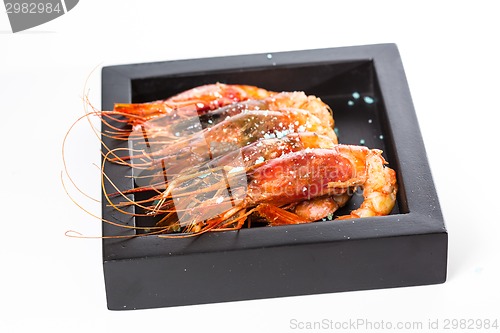 Image of grilled shrimp in black plate on white background.