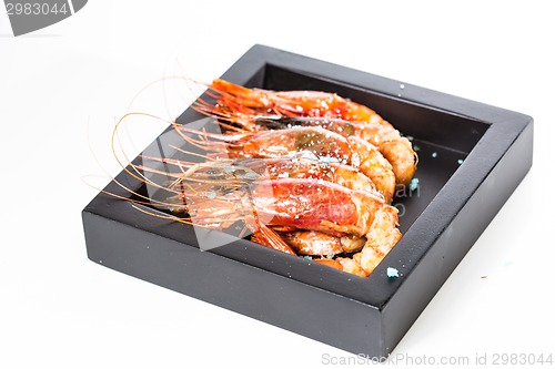 Image of grilled shrimp in black plate on white background.