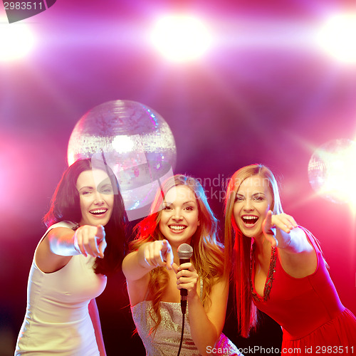 Image of three smiling women dancing and singing karaoke