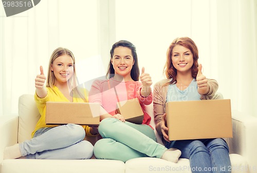 Image of smiling teenage girls with cardboard boxes at home